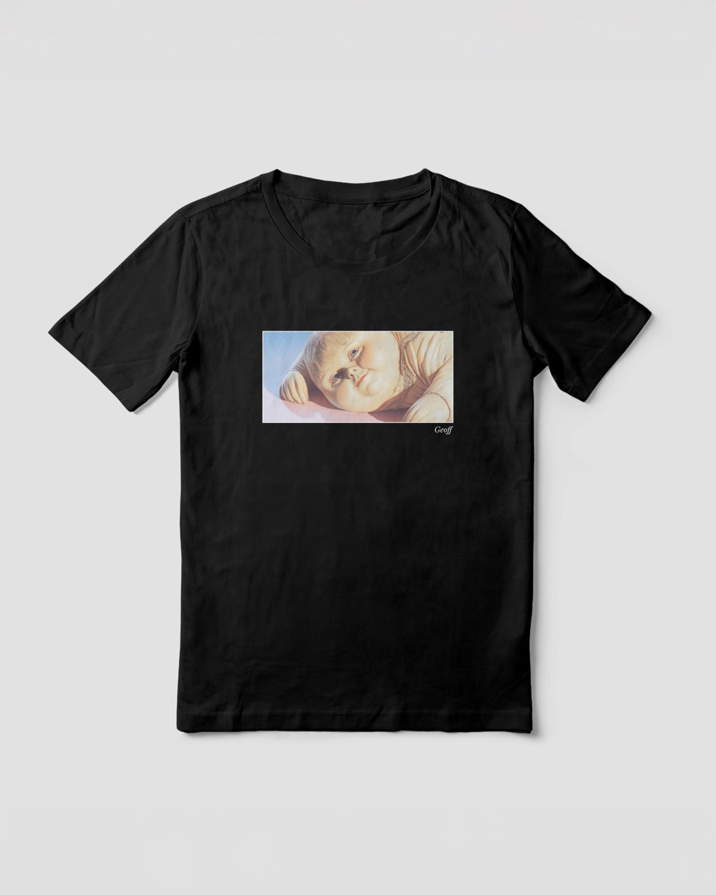 a black organic cotton t-shirt featuring a close-up, half-frame graphic print of a jolly, proud boy (Geoff) looking slightly upwards, with his name 'Geoff' subtly printed in Libre Baskerville below the image. The t-shirt has a dreamy aesthetic