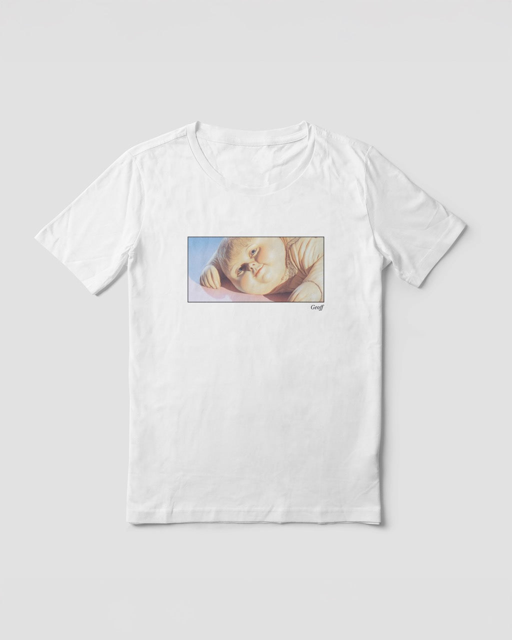 a white organic cotton t-shirt featuring a close-up, half-frame graphic print of a jolly, proud boy (Geoff) looking slightly upwards, with his name 'Geoff' subtly printed in Libre Baskerville below the image. The t-shirt has a dreamy aesthetic
