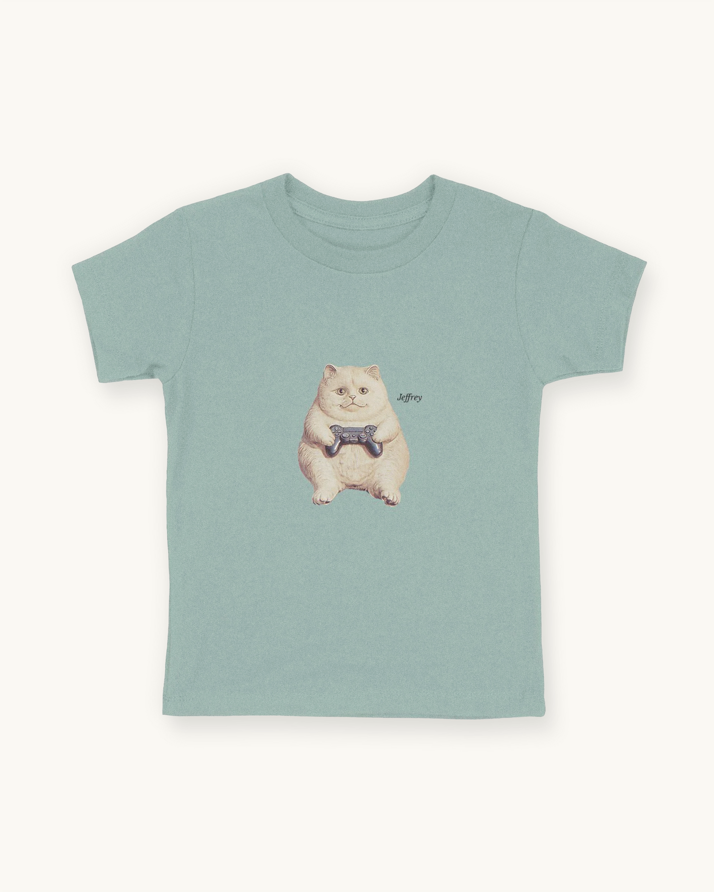 Fitted children's blue green tee with a front print cutout of the cat Jeffrey gaming with this name in Libre Baskerville.