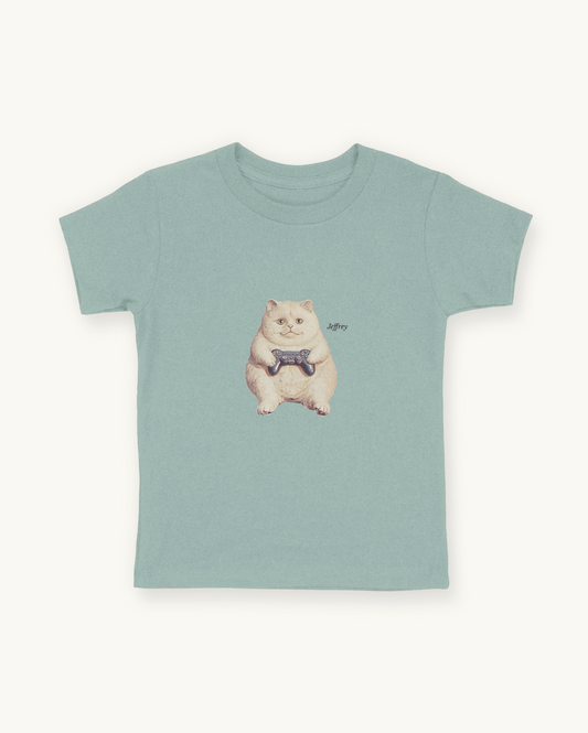 Fitted children's blue green tee with a front print cutout of the cat Jeffrey gaming with this name in Libre Baskerville.