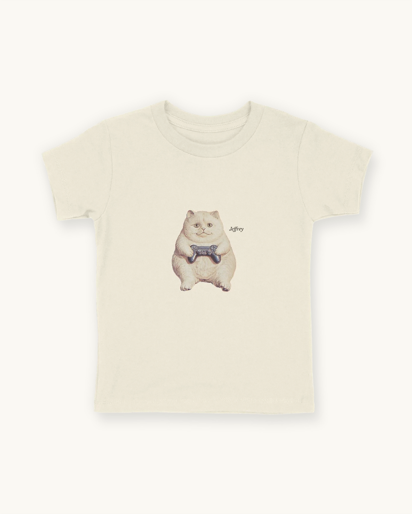 Fitted children's natural white tee with a front print cutout of the cat Jeffrey gaming with this name in Libre Baskerville.