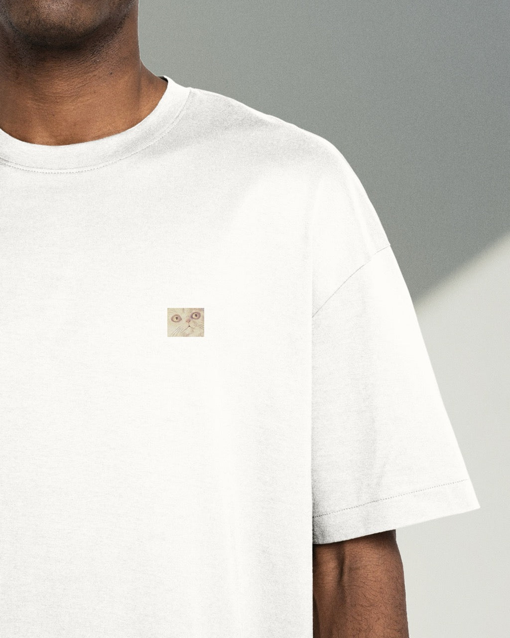 Model wearing white organic cotton Geoff & Jeffrey, front of t-shirt with a small close up of Jeffrey’s face. The t-shirt has a minimal design.