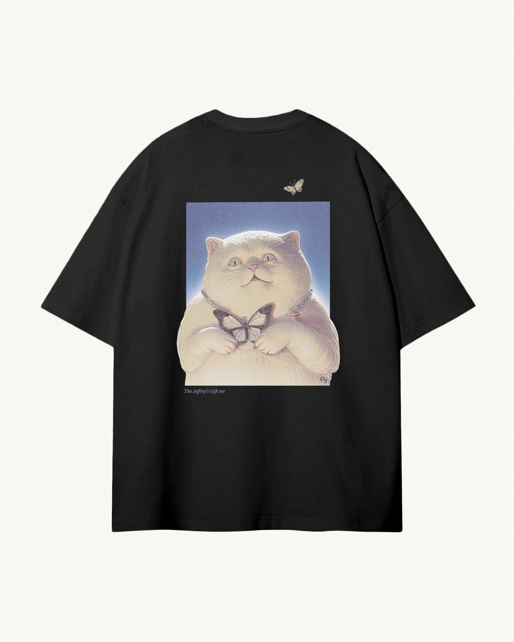 black organic cotton Geoff & Jeffrey unisex t-shirt with drop shoulders and a large graphic backprint of the cute cat Jeffrey holding a butterfly,with the title printed below. The shirt has a cool aesthetic.