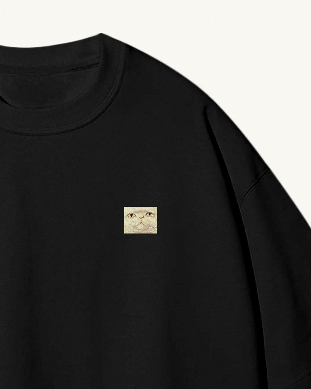 black organic cotton Geoff & Jeffrey unisex t-shirt with drop shoulders. The front of the shirt has a small close up of Jeffrey’s weird face and a minimal design.