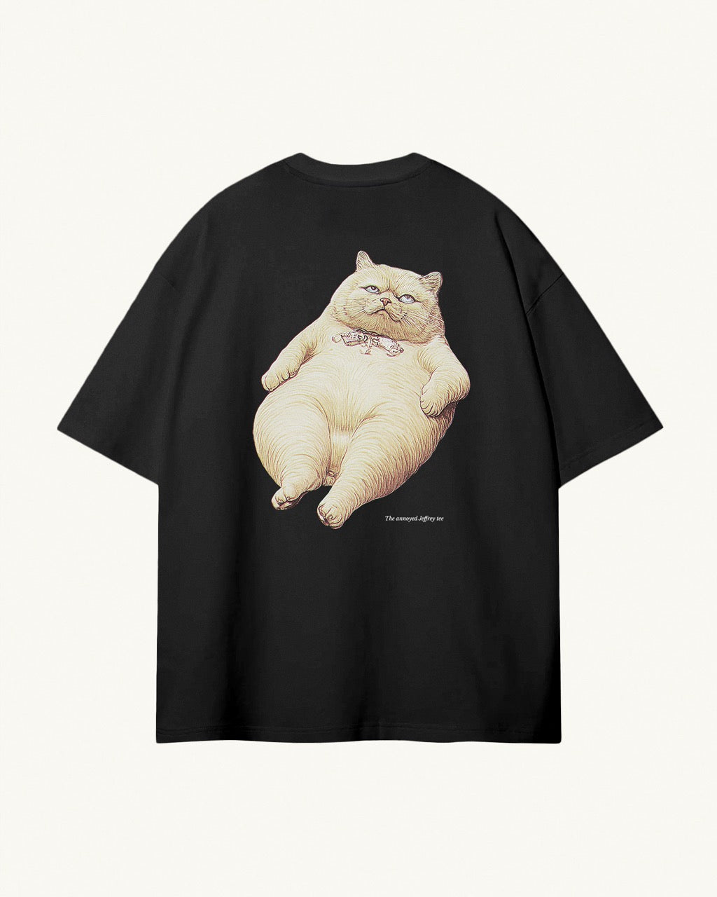 Black organic cotton Geoff & Jeffrey unisex t-shirt with drop shoulders and a large graphic backprint of a funny fat cat (Jeffrey) looking annoyed, and the title printed below. The shirt has a cool aesthetic.
