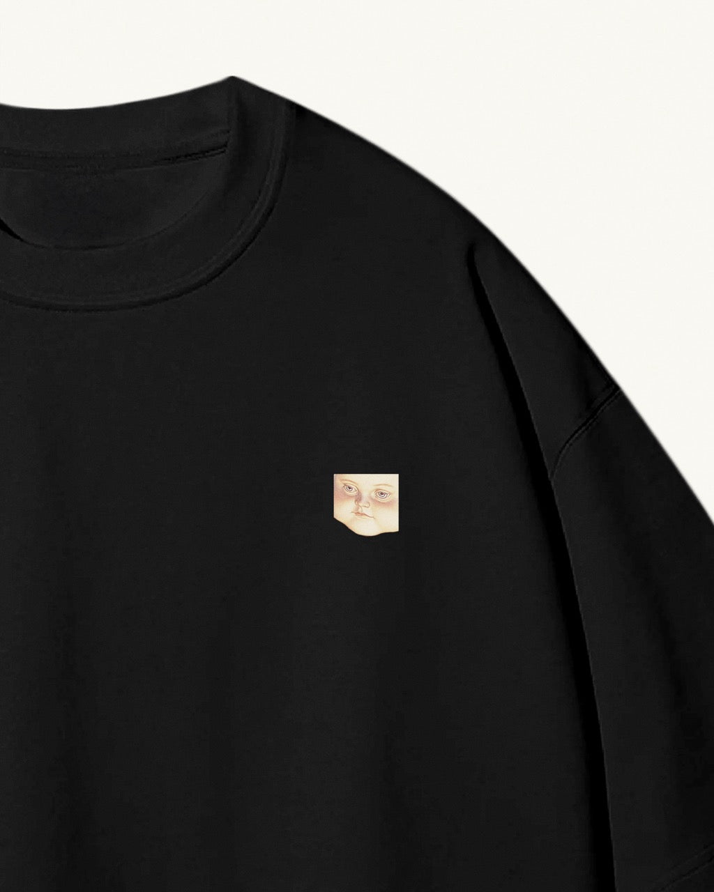 close up of a black organic cotton Geoff & Jeffrey unisex t-shirt with drop shoulders. The front of the shirt has a small close up of geoff’s face and a minimal design.