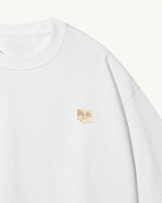 close up of a white organic cotton Geoff & Jeffrey unisex t-shirt with drop shoulders. The front of the shirt has a small close up of geoff’s face and a minimal design.