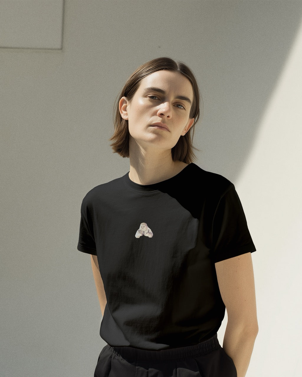 Model in a women's black organic cotton Geoff & Jeffrey t-shirt with a mall graphic print of a jolly, proud boy (Geoff) holding a butterfly. The t-shirt has a cute silly aesthetic.