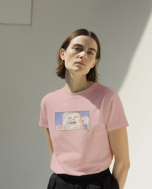 Woman in a women's pink organic cotton Geoff & Jeffrey t-shirt with a framed graphic print of a jolly, proud boy (Geoff) looking upwards holding drinks for apero, with his name 'Geoff' subtly printed in Libre Baskerville below the image. The t-shirt has a feel good aesthetic.