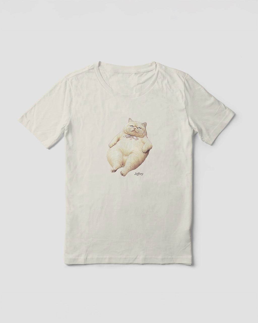 Mock up of a women's t-shirt in off-white, natural color with a front print illustration of Jeffrey (from the funny duo Geoff & Jeffrey). The fat cat is lying on his back, looking annoyed, rolling his eyes. In the bottom his name is written in an elegant font: Libre baskerville.