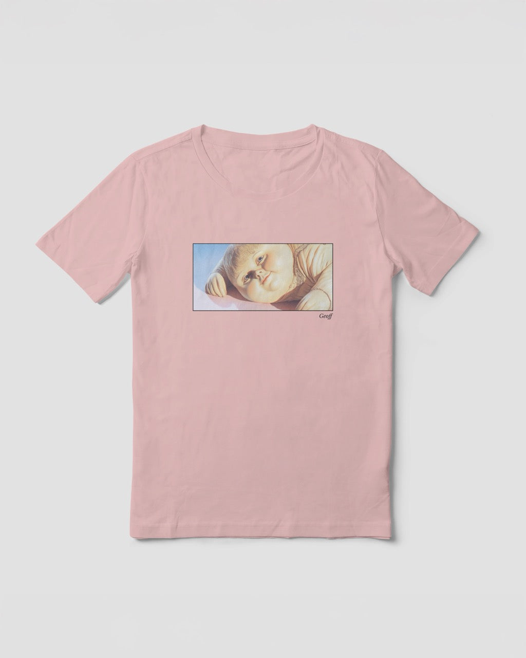 Women's soft pink organic cotton Geoff & Jeffrey t-shirt with a framed graphic print of a jolly, proud boy (Geoff) looking slightly upwards, with his name 'Geoff' subtly printed in Libre Baskerville below the image. The t-shirt has a dreamy aesthetic