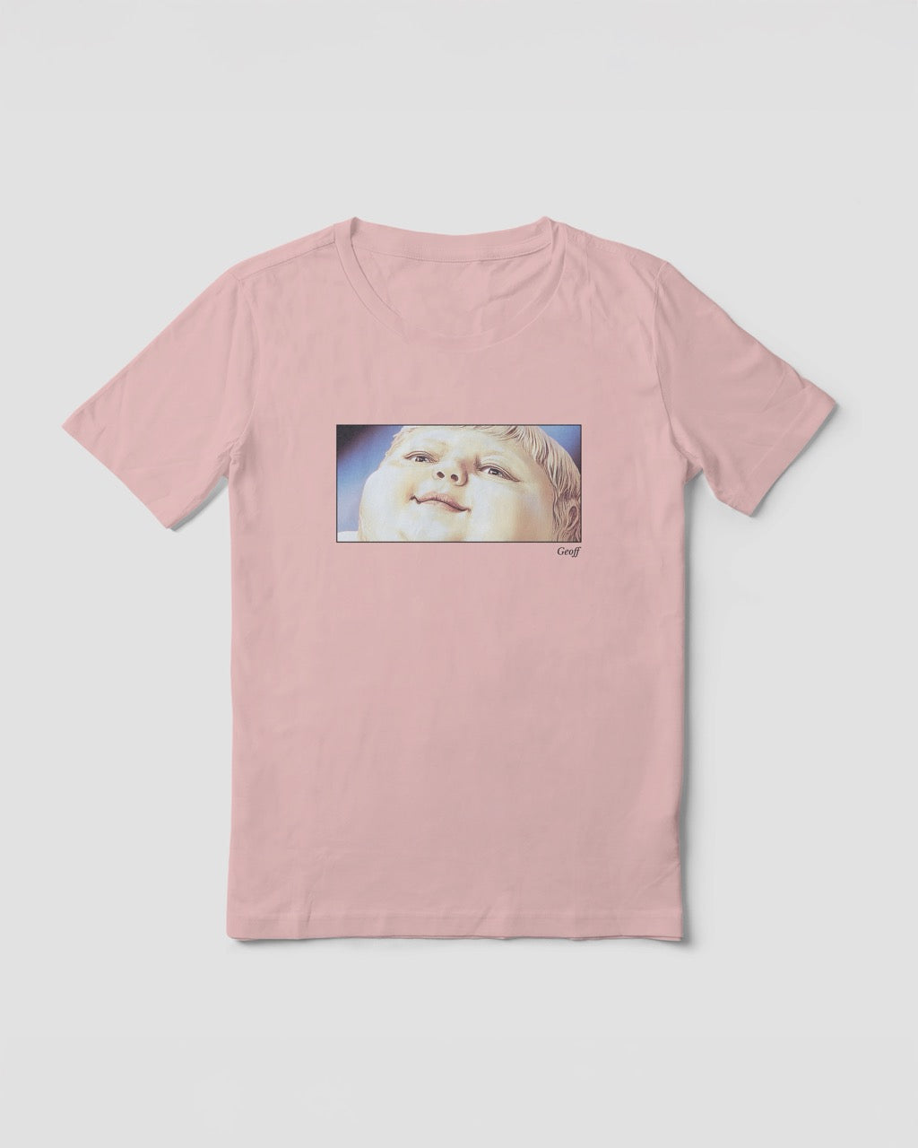 Women's soft pink organic cotton Geoff & Jeffrey t-shirt with a framed graphic print of a jolly, proud boy (Geoff) looking upwards, smiling, with his name 'Geoff' subtly printed in Libre Baskerville below the image. The t-shirt has a feel good aesthetic
