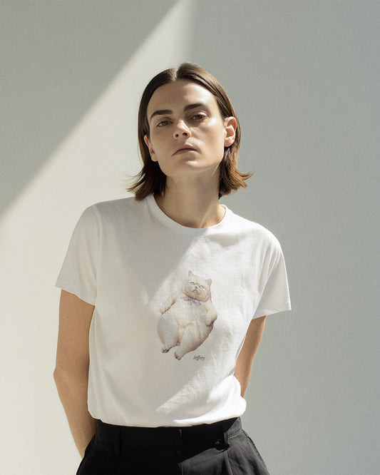 Women's t-shirt in white with a front print illustration of Jeffrey (from the funny duo Geoff & Jeffrey). The fat cat that is lying on his back, looking annoyed, rolling his eyes. In the bottom his name is written in an elegant font: Libre baskerville