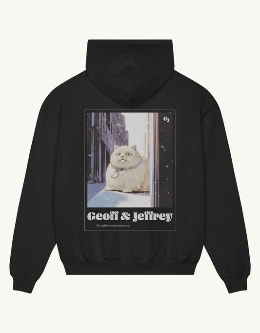 Black organic cotton Geoff & Jeffrey hooded sweater with drop shoulders  and a large graphic backprint of a joyful, fat cat in the snowy city with the brandname in ohno blazeface and title in libre baskerville printed below.